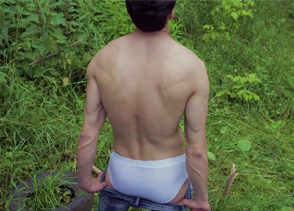 Sexy guy in jeans poses front and back outdoor
