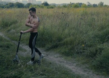 Teen muscle guy poses after riding a scooter