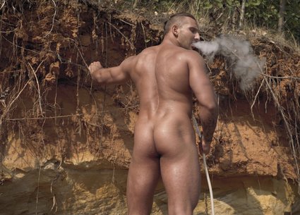 Muscle man smoking naked on the beach